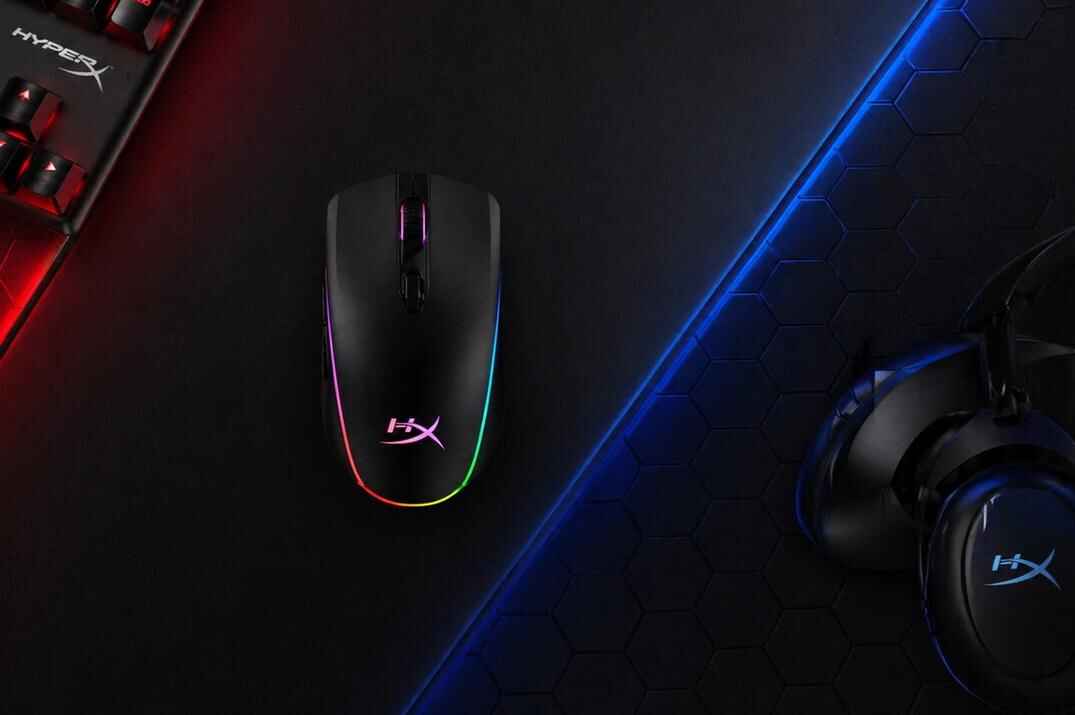 HyperX gaming mouse with RGB lighting on a dark gaming desk with keyboard, headset, and red-blue neon accents